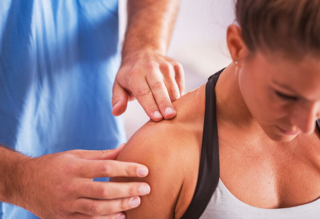 Physician examining woman with pain in trapezius muscle