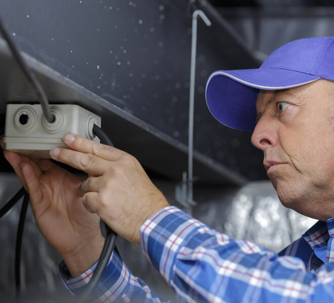 Electrician with workers' compensation working on the job examining electrical outlet